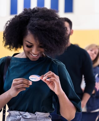 Young woman putting a I Just Voted sticker on her shirt