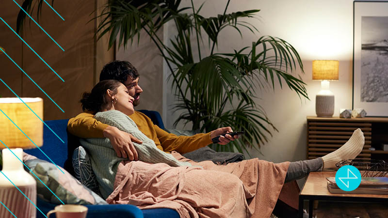 Couple on couch watching OTT content with ads from a targeted marketing campaign
