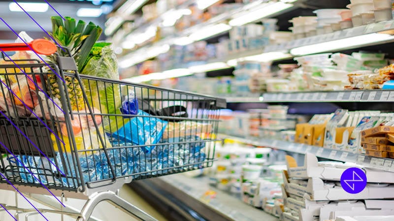 Cart with CPG products in blue packaging in-store next to a refrigerated case